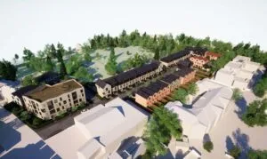 Digital visualisation looking down on the rooftops of the new homes. Facing the street is a light brick coloured block of apartments four-storeys high, behind which are a series of pitched rooved three-storey houses. Tree and open land are shown in the background.